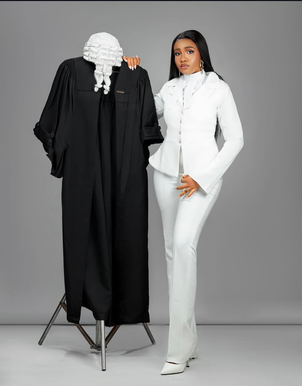 Chidalu in a white suit beside her barrister's gown and wig